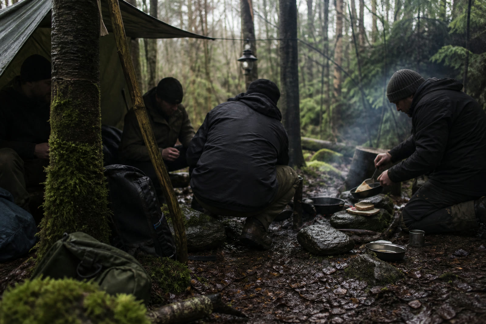 Men preparing simple food beneath a tarp in a wet forest