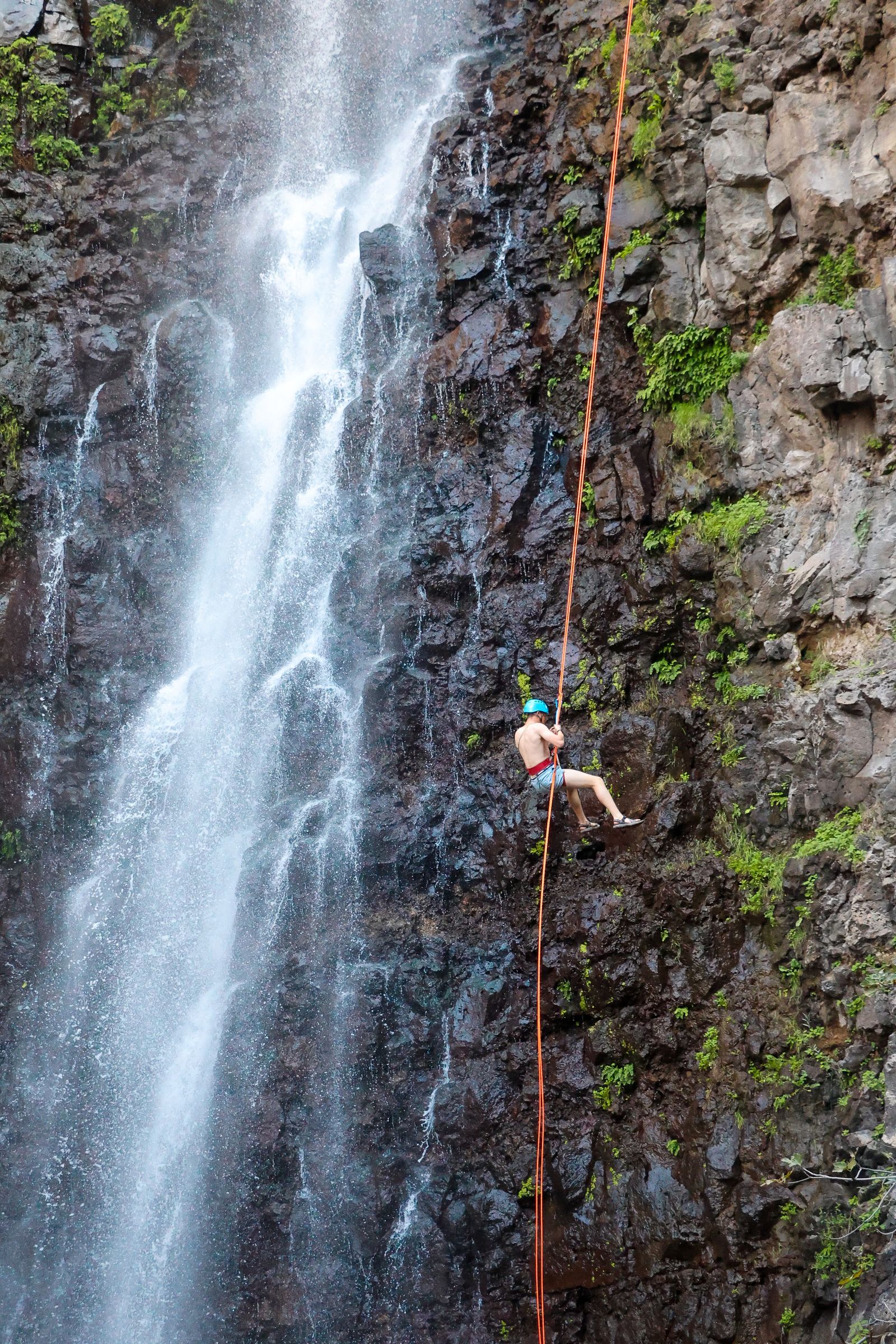 Canyoner rappelling beside a waterfall