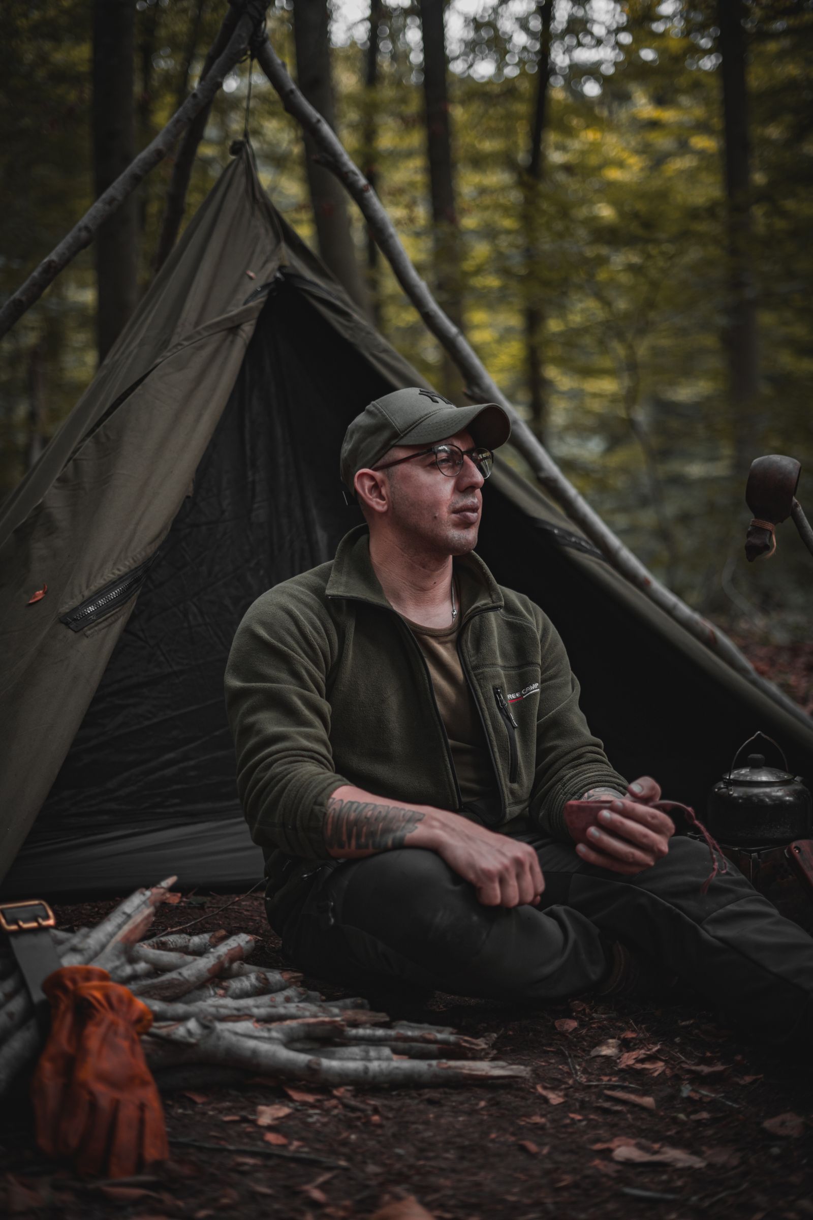 A person sitting alone beside a forest bivouac
