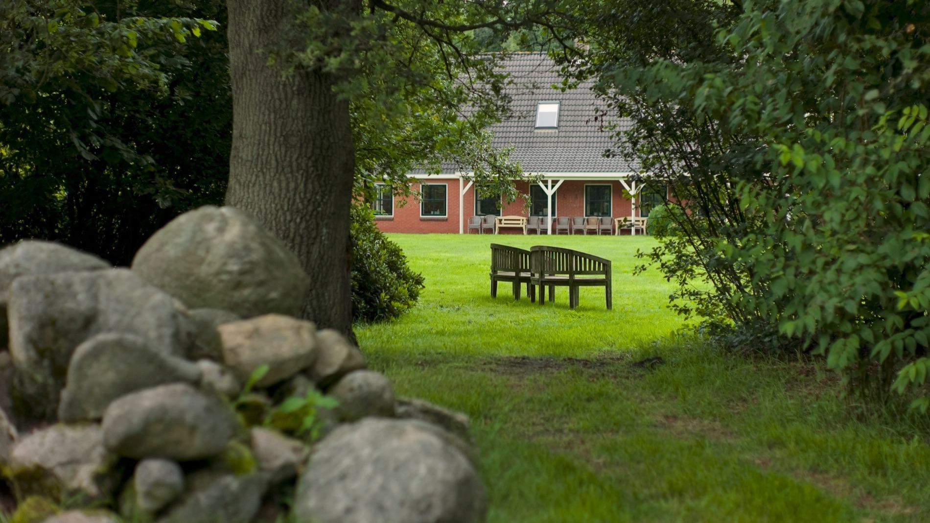 The main New Eden house and its roof seen through mature trees